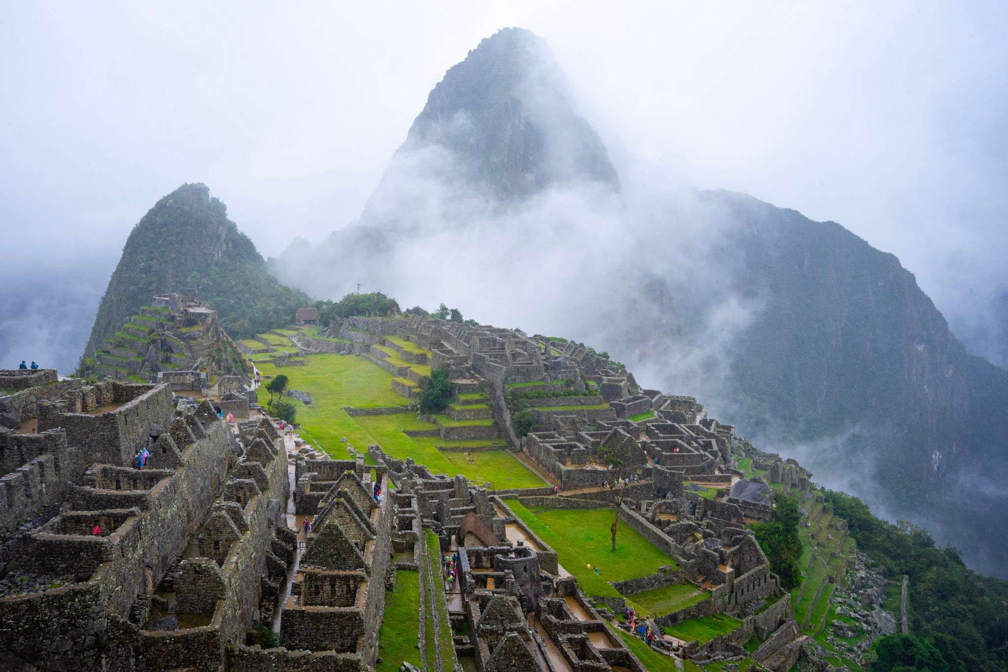 Aerial view of Machu Picchu ruins surrounded by misty green mountains